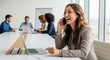 © zabhie - Happy Businesswoman Laughing on the Phone During a Meeting. Professional female manager enjoys successful communication and multitasking in the office