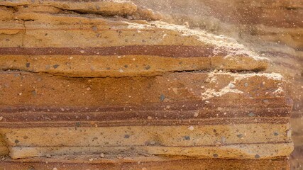 Wall Mural - Handheld camera captures detailed texture of freshly cut sandstone layers with dust particles in the air.