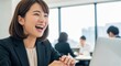 © Stingray_Japan - チャットやオンライン会議で相手のリアクションに爆笑している元気な日本人女性社員