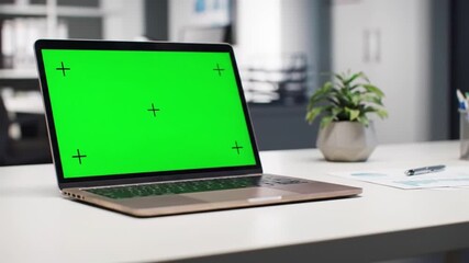 Modern Laptop with Green Screen on a Desk in an Office Setting.