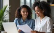 © hao - Sharing experience. Capable young indian female mentor explaining student intern corporate work principles using laptop and paper documents, two diverse women colleagues discussing business project