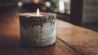 © Khadiza F - Awesome photo of burning candle in a concrete holder on a wooden table in a dark room.