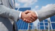 © CStock - Two professionals shake hands in front of solar panels, symbolizing partnership and renewable energy commitment.