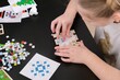 © marishkaTR - A girl makes a Christmas toy with her own hands from ceramic mosaic. Ceramic mosaic, DIY Christmas tree toy. Eco-friendly toy, educational activity for children.