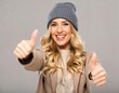 © Babang - Smiling woman in a beanie gives two thumbs up