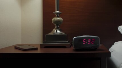 Wall Mural - In a dark room, an alarm clock glows on a nightstand. A person turns on the light and shuts off the alarm, ideal for morning, sleep, and lifestyle visuals.