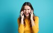 © Joseph - Irritated nervous stressed Caucasian woman talking screaming on two mobile phones having conversation conflict quarrel complaint dispute discuss solve problem. Young girl isolated on blue background