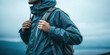 © Naret - Man wearing blue rain jacket with backpack ready for travel and adventure in misty outdoor environment