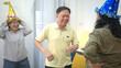 © Wosunan - Happy elderly man blowing out birthday candles surrounded by friends