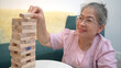© Wosunan - On a holiday, an elderly man enjoys jenga game in living room of house