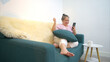 © Wosunan - On a holiday, an elderly woman relaxes with a smartphone on the sofa