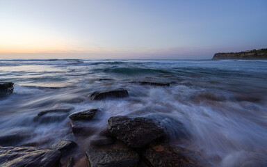 Wall Mural - Wave water flowing between rocks on the shore.