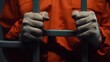 © Varos - Hands gripping jail bars in an orange prison jumpsuit, symbolizing confinement and justice