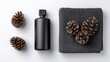 © W saputro - Flat lay composition features pine cones, towel, and a black bottle on white