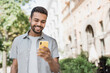 © kite_rin - Young handsome student man using smartphone. Smiling joyful guy summer portrait. Cheerful men holding mobile phone in a city
