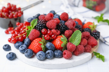 Wall Mural - Different ripe berries and mint leaves on white tiled table, closeup