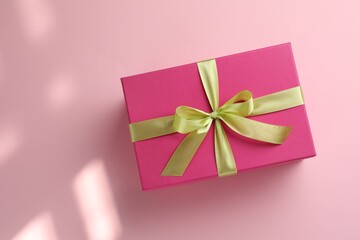 Wall Mural - Beautiful gift box with bow on pink background, top view. Space for text