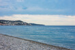 Beautiful view of wavy sea, city and pebbles on beach