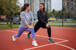 © Dexon Dee - Two young women stretching legs on outdoor court