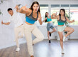 © JackF - Female teenager performs movements during warm-up, limbering-up part of workout together with peers. Group of young girls and guy dance modern groove in fitness club.