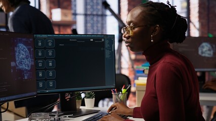 IT technician in startup office using large language model to get help with coding project. IT specialist interacting with AI LLM chatbot on PC in software development business company, camera B