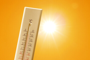 Wall Mural - thermometer showing high temperature against orange sky with bright sun. extremely hot weather