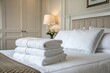 © Muhammad - Cozy hotel room with neatly stacked towels on a made bed, soft lighting, and floral decor