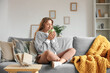 © Pixel-Shot - Beautiful young happy woman with cup of tea sitting on sofa at home
