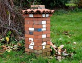Brick garden pillar with tiled roof on green grass