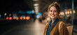 © benjamin - A portrait of a happy woman in a blurred urban night setting smiles at the camera, evoking the sense of adventure and confidence.  She is against the night scene background.