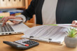 © Nanci - Auditor using laptop and calculator to analyze financial reports and prepare a business budget, reviewing numbers and paperwork at a desk with focused concentration