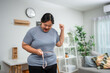 © Kawee - Asian young overweight woman measuring waist with tape measure at home.