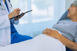 © ArLawKa - Doctor is examining elderly female patient in ward while doctor is checking her condition in recovery room. Medical and healthcare concept.