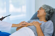 © ArLawKa - Elderly female doctor and Asian female patient are discussing something while sitting on hospital bed. Medical consultation concept.