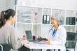 © ArLawKa - Doctor and patient discussing various matters while sitting at a table. Medical and healthcare concept. Doctor and patient.