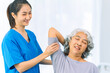 © ArLawKa - Young nurse trains elderly woman to exercise her arm during therapy and rehabilitation in her living room at home. Physical therapist.