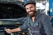 © Vitalii Shkurko - A mechanic wearing a checkered shirt and cap is happily repairing a car in a busy workshop. Tools are scattered around, showcasing the environment of auto maintenance and service