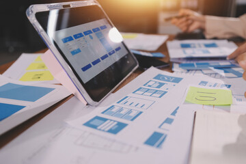 Close up ux developer and ui designer brainstorming about mobile app interface wireframe design on table with customer breif and color code at modern office.Creative digital development agency.