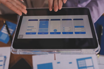 Close up ux developer and ui designer brainstorming about mobile app interface wireframe design on table with customer breif and color code at modern office.Creative digital development agency.
