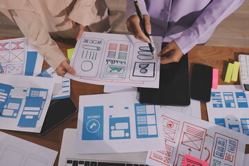 Close up ux developer and ui designer brainstorming about mobile app interface wireframe design on table with customer breif and color code at modern office.Creative digital development agency.