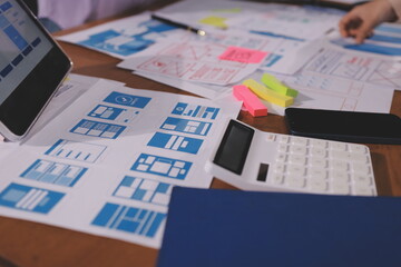Close up ux developer and ui designer brainstorming about mobile app interface wireframe design on table with customer breif and color code at modern office.Creative digital development agency.