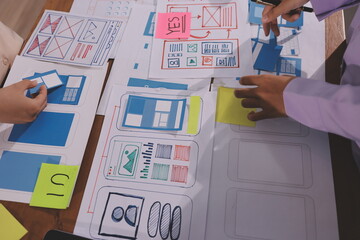 Close up ux developer and ui designer brainstorming about mobile app interface wireframe design on table with customer breif and color code at modern office.Creative digital development agency.