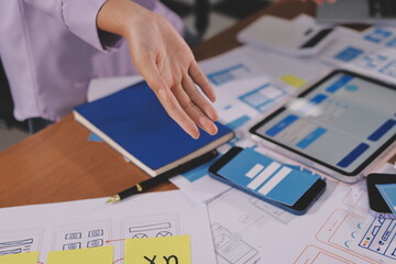 Close up ux developer and ui designer brainstorming about mobile app interface wireframe design on table with customer breif and color code at modern office.Creative digital development agency.