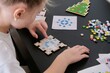 © marishkaTR - A girl makes a Christmas toy with her own hands from ceramic mosaic. Ceramic mosaic, DIY Christmas tree toy. Eco-friendly toy, educational activity for children.