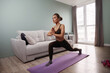 © verona_studio - Woman practicing yoga in living room while wearing athletic clothes and focusing on stretching and strengthening her body during morning routine