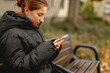 © tan4ikk - In Spring, A Girl In Glasses Sits On A Bench With A Smartphone