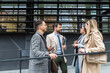 © Srdjan - IT experts freelance workers innovative technology developers, working on a new project staff meeting with casual talk in formalwear outside office building before the work. Discussing business people
