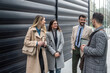© Srdjan - IT experts freelance workers innovative technology developers, working on a new project staff meeting with casual talk in formalwear outside office building before the work. Discussing business people