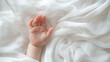 © syhin_stas - Newborn infant fingers curling softly against pure white cotton, revealing fragile skin texture and embodying vulnerability of early childhood moments