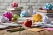 © Suhardi - A messy wooden desk with an apple, scattered crumpled paper, stationary and books